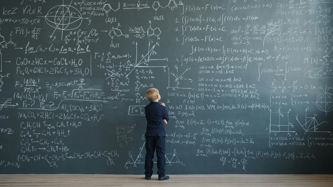 Child looking at mathematical formulas on a chalkboard
